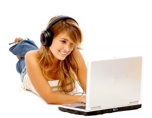 Casual student listening to music on the computer while studying isolated over a white background