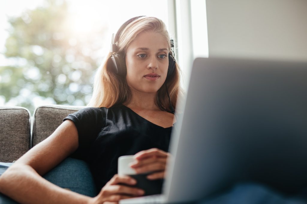 Young woman with headphones looking at laptop