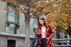 pretty young woman walking on the street using smartphone