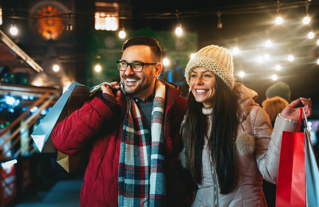 Happy couple having fun together on Christmas shopping. Holiday present people happiness concept