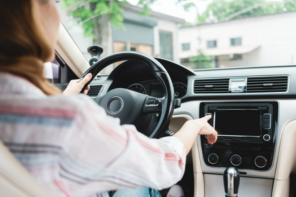 partial view of woman turning on radio while driving car