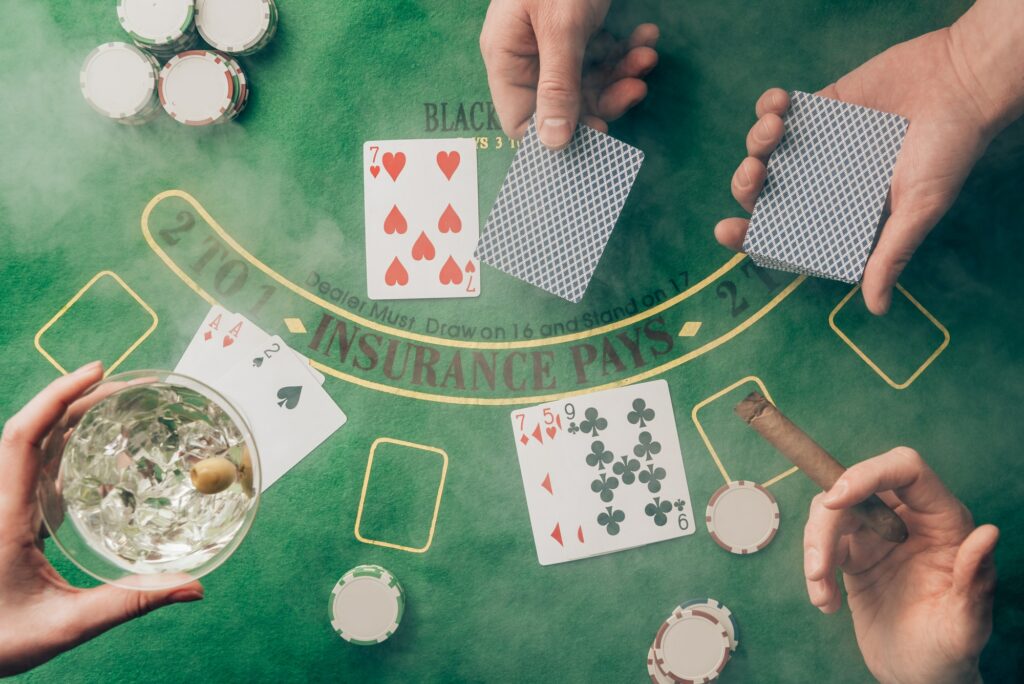 Smoke over people playing black jack by casino table with cards and chips