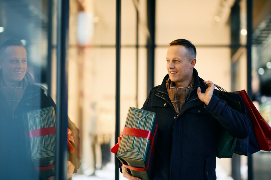 Happy man enjoying in window shopping for Christmas holidays.