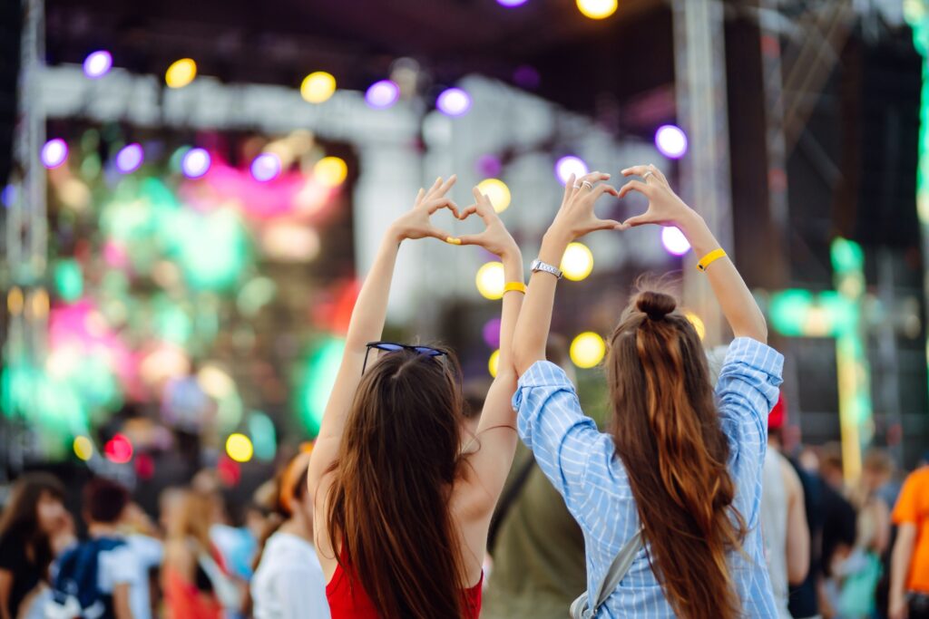 Heart shaped hands at concert. Music concert with lights and silhouette of people enjoying concert. Heart shaped hands at concert. Music concert with lights and silhouette of people enjoying concert.