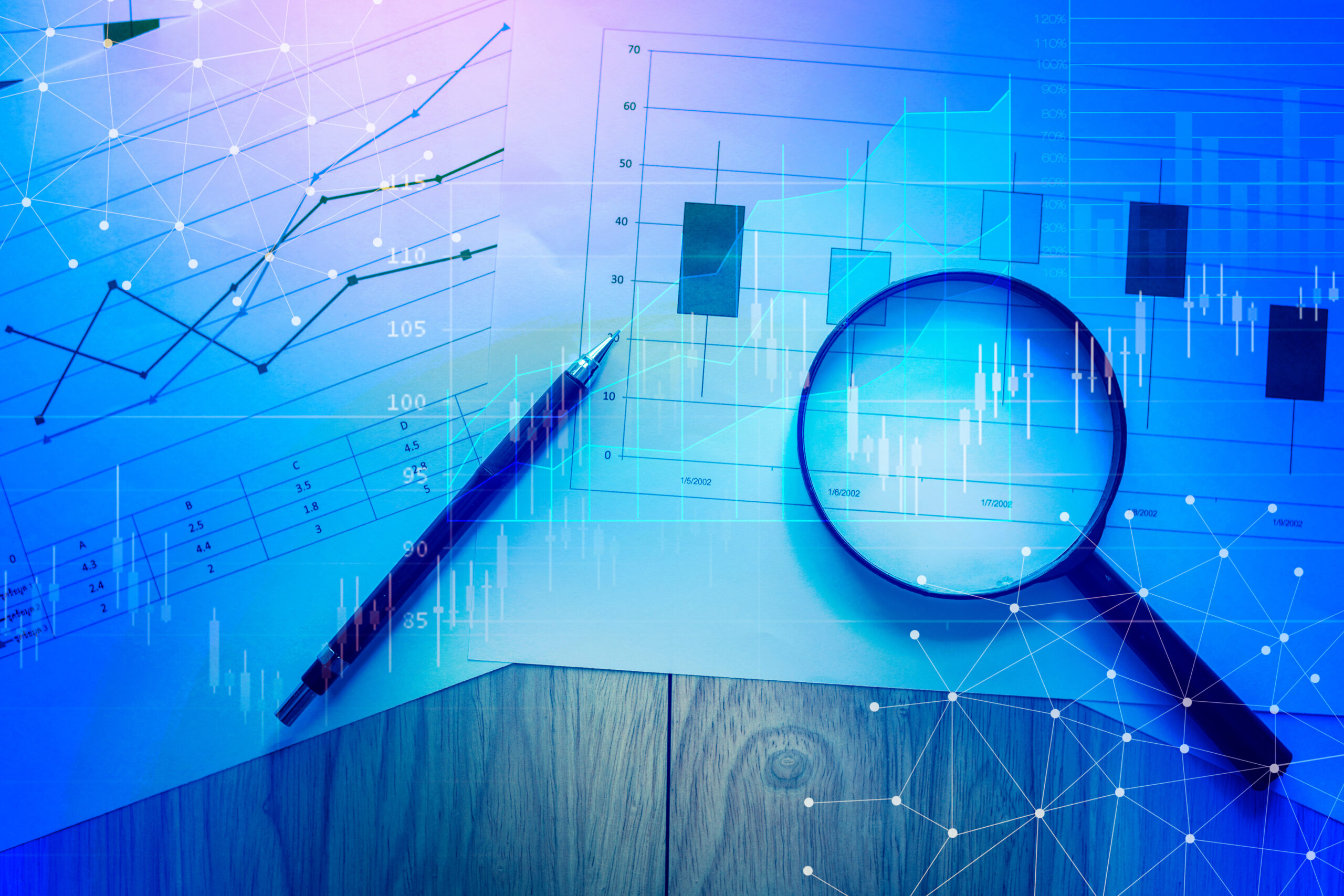 Magnifying glass and documents with analytics data lying on tabl